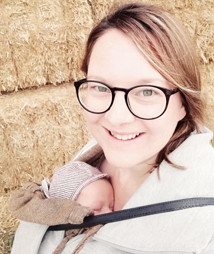 Josie lächelt mit ihrem Baby im Tragetuch