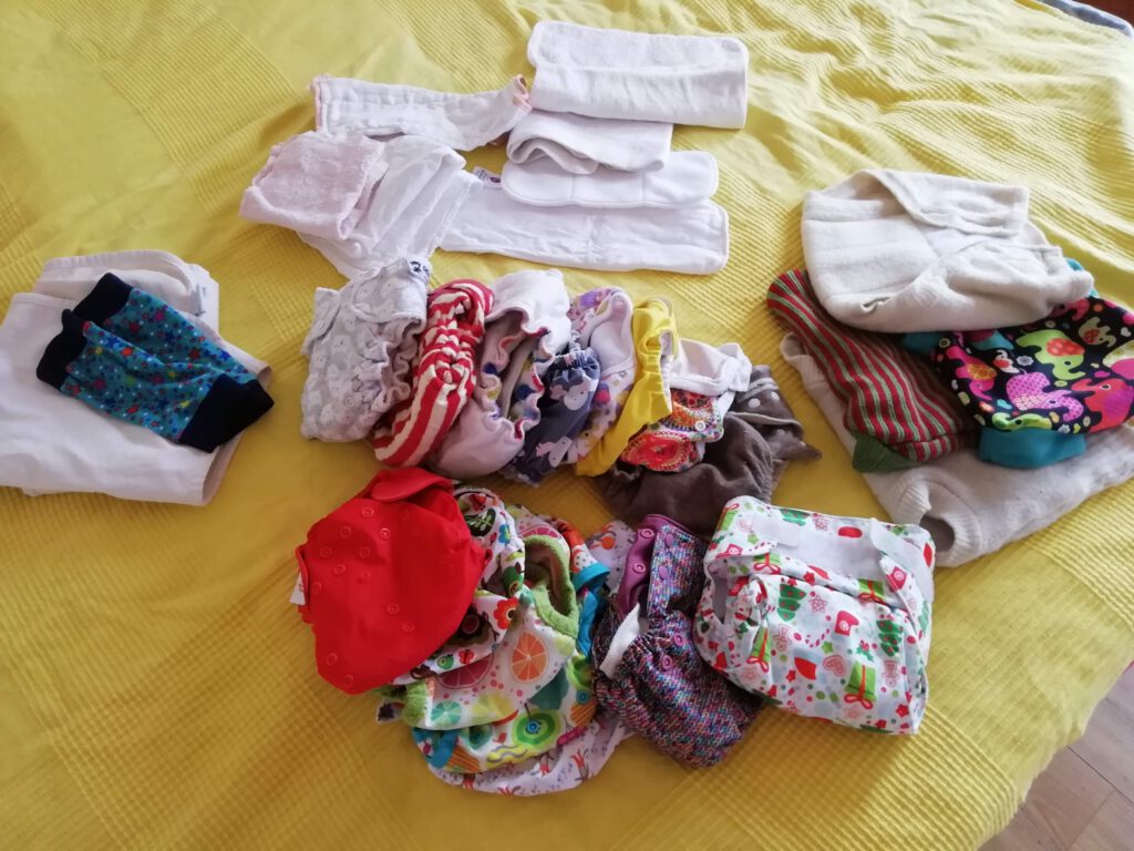 Bunte Stoffwindeln und Überhosen ausgebreitet auf einem Bett